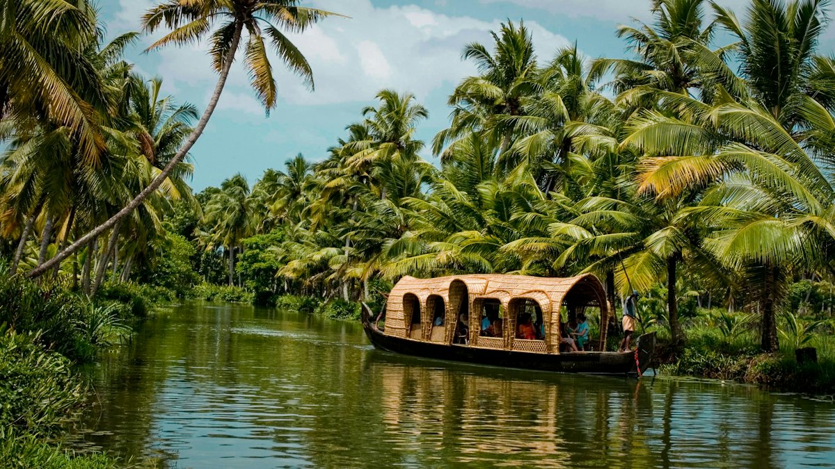 A thatched houseboat on a palm-lined backwater canal in Kerala