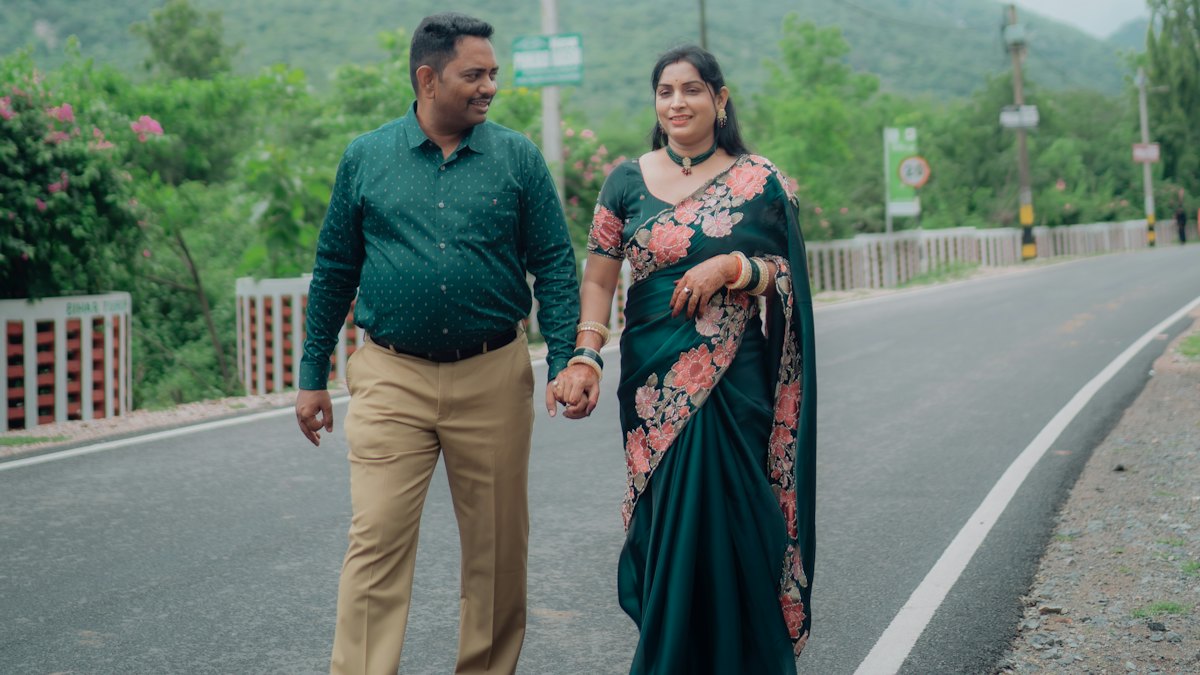 A smiling couple walking hand in hand along a hill road